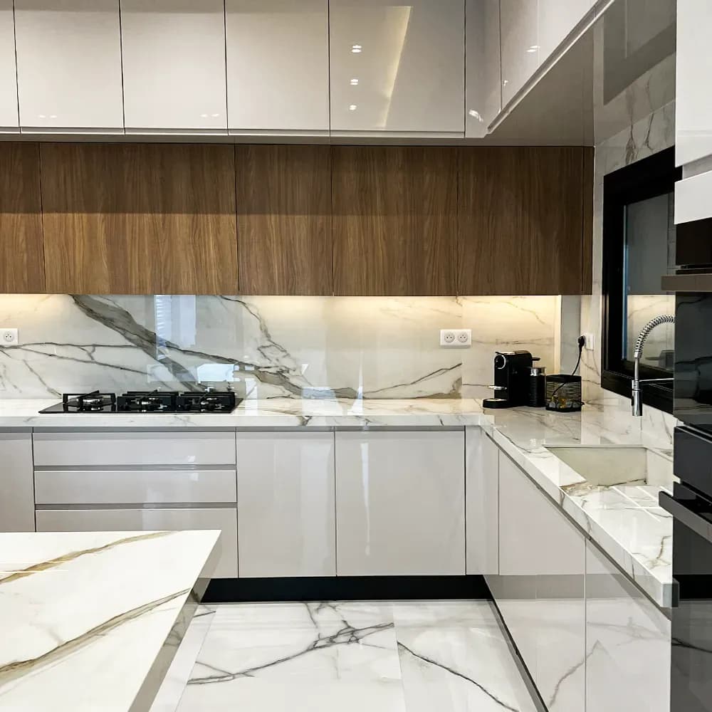 Cuisine Cuisina contemporaine avec façades blanches brillantes, éléments en bois, plan de travail effet marbre et électroménager encastré.